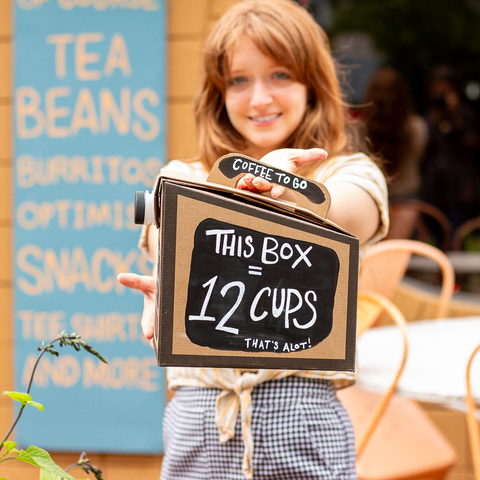 employee holding a to go box of roosroast coffee