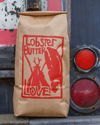 Brown paper bag with red lobster design and 'Lobster Butter Love' text against a textured background.