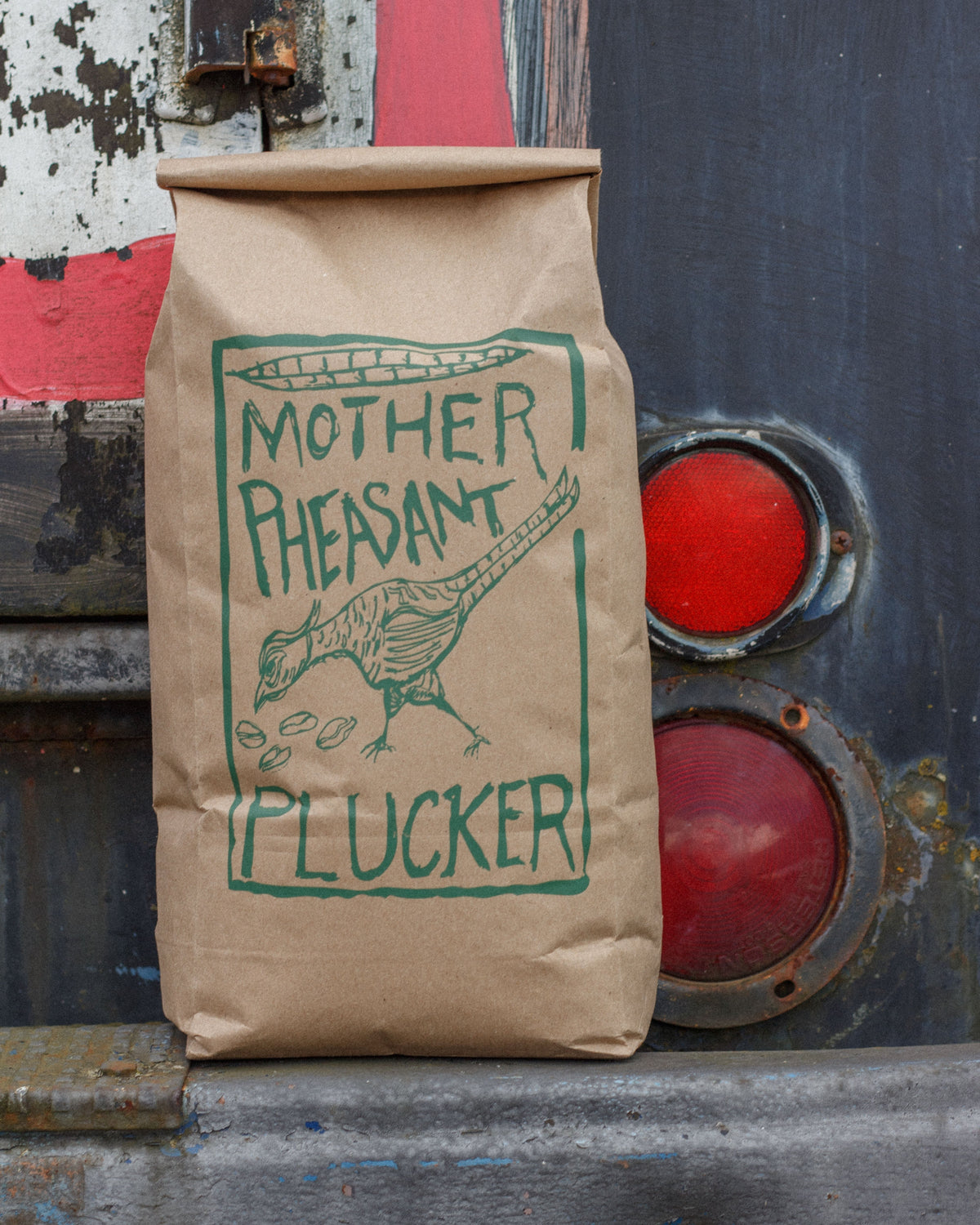 Brown paper bag with green text and logo on a rustic metal background