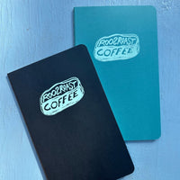 Black and teal moleskin journals with RoosRoast logo.