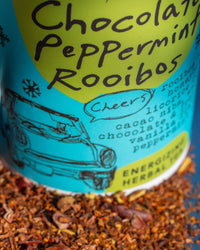 Tea packaging with 'Chocolate Peppermint Rooibos' text and illustrations on a blue and yellow background.