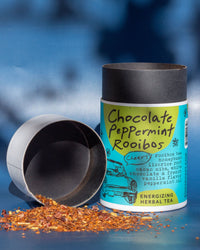 Tea canister labeled 'Chocolate Peppermint Rooibos' with tea leaves spilling out on a blue background