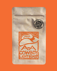 Coffee package with cowboy hat design and 'Cowboy Light Roast' text on an orange background