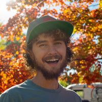 smiling while wearing gray trucker hat