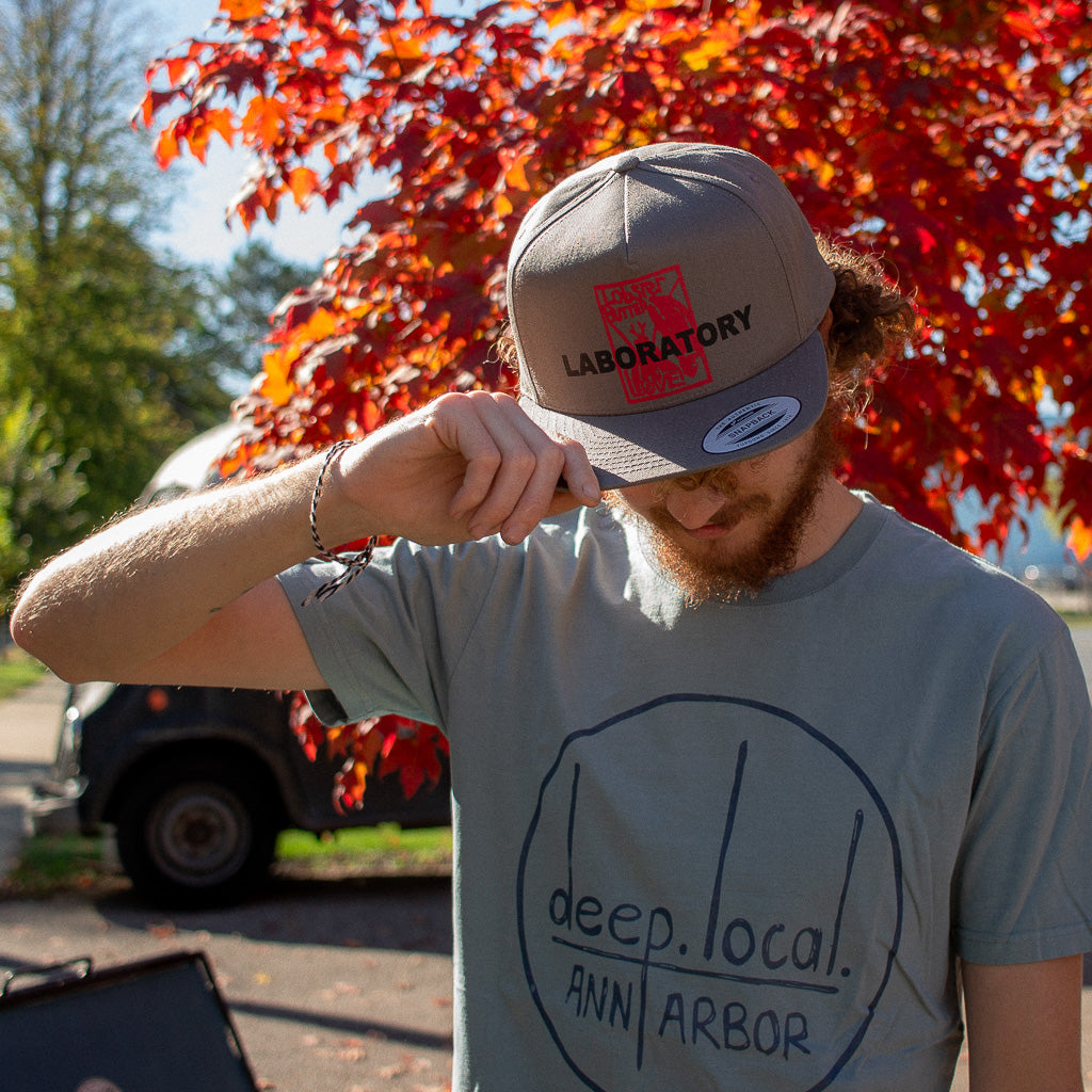 hand on brim of gray trucker hat 