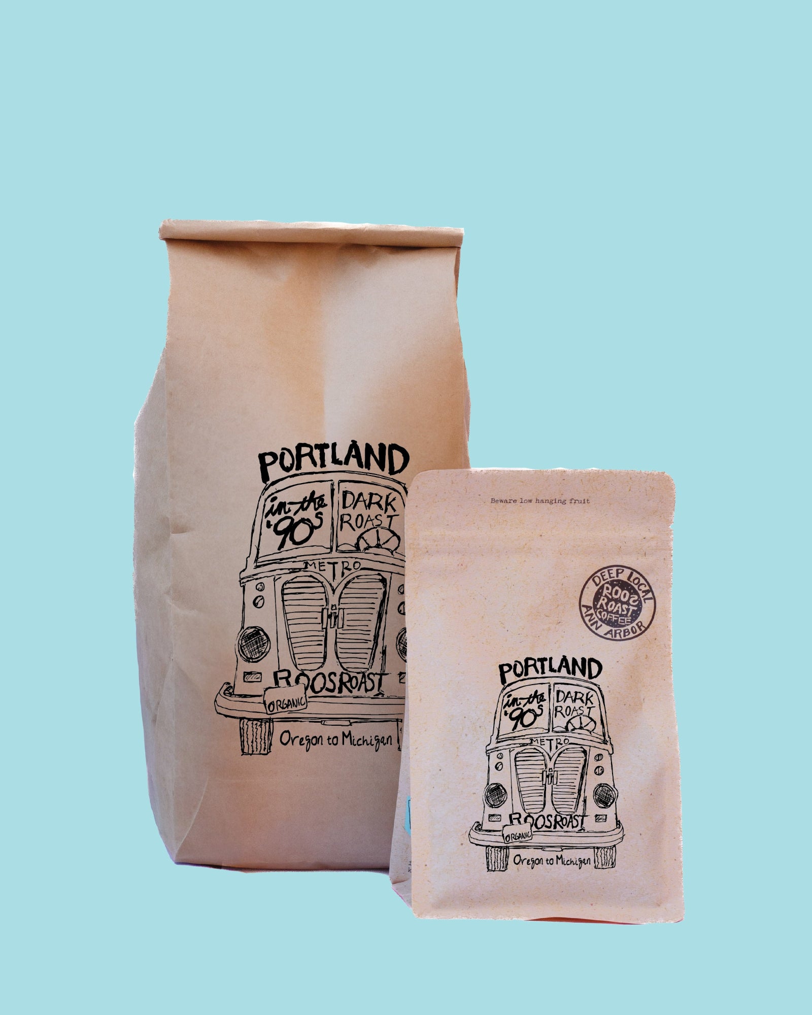 Two paper coffee bags from Portland Dark Roast Coffee Co. on a solid light blue background.