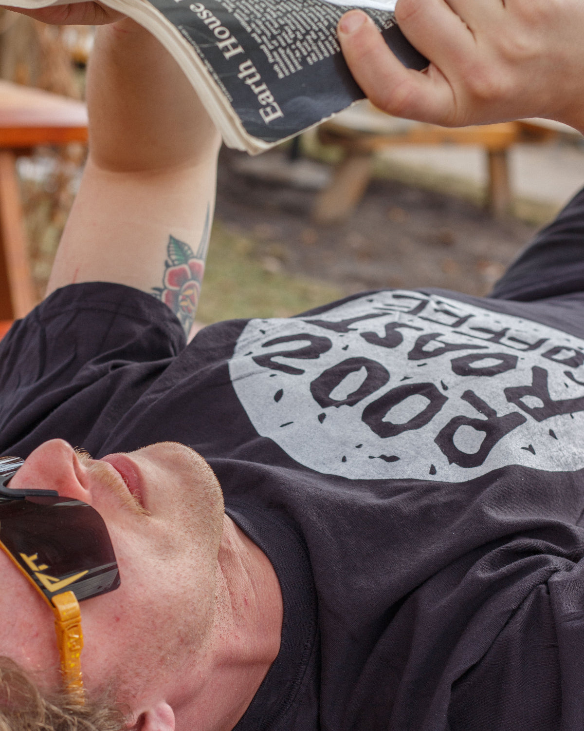 Person lifting weights with a 'Rooz' t-shirt on, outdoors.