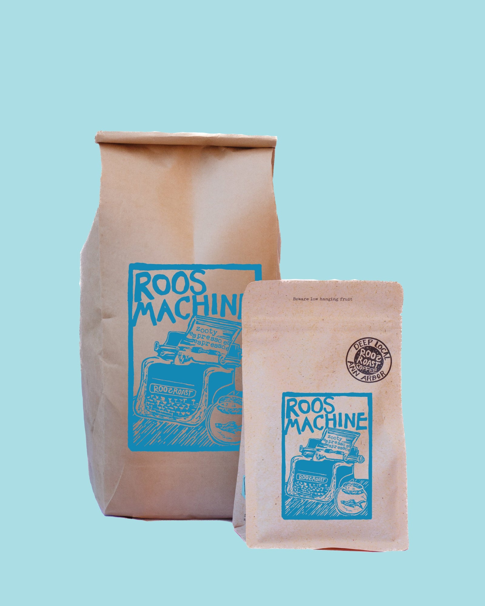 Two Roos Machine branded kraft paper bags, one larger standing bag and one smaller pouch in front, both with blue printed graphics, on a solid light blue background.