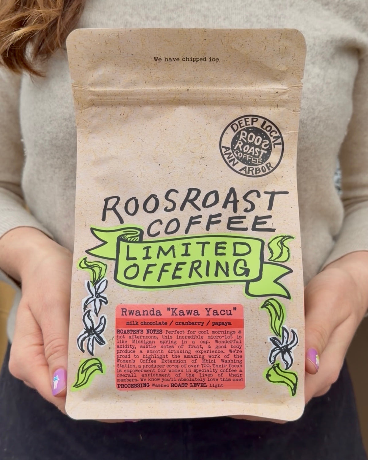Person holding a Roosroast Coffee package with branding and product details.