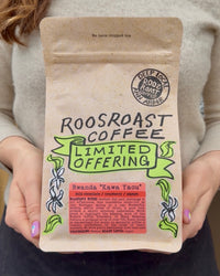 Person holding a Roosroast Coffee package with branding and product details.